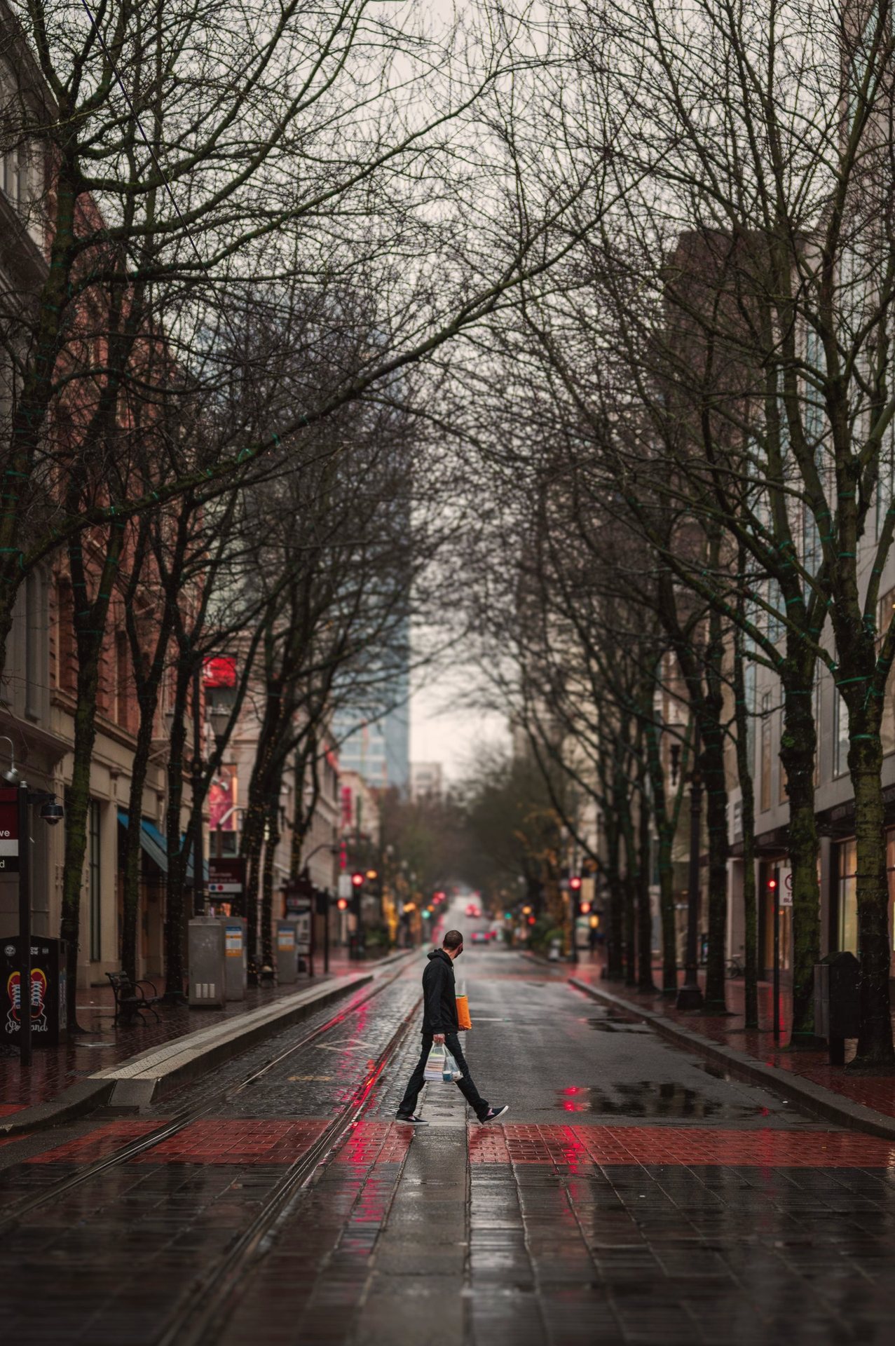 Adult walking alone on a rainy Pacific Northwest city street in the morning
